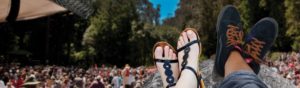 two feet in sandals propped up in front of an outdoor crowd