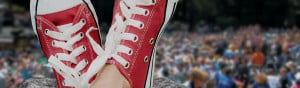 two tennis shoes propped up in front of an outdoor crowd